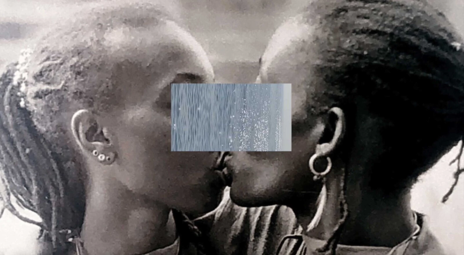A grey rectangle covers the eyes and noses of two people with dark-brown skin kissing