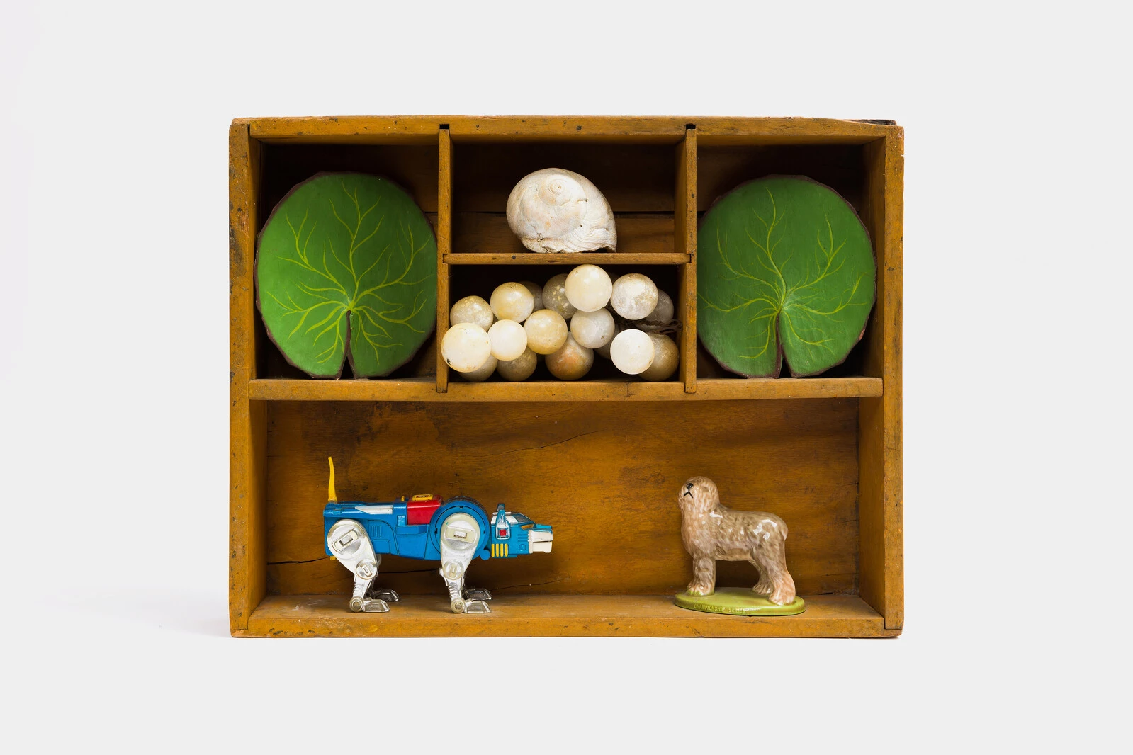 Kenzi Shiokava, <em>Untitled</em>, n.d. Wood shelf, toy figurines, seashell, faux grapes, and leaves; 13 1/2 × 17 1/2 × 5 1/2 in. (34.3 × 44.5 × 14 cm). Courtesy the Estate of Kenzi Shiokava and Nonaka-Hill, Los Angeles & Kyoto. Photo: Taka Nonaka-Hill. 2025/10/DSC5910.jpg 