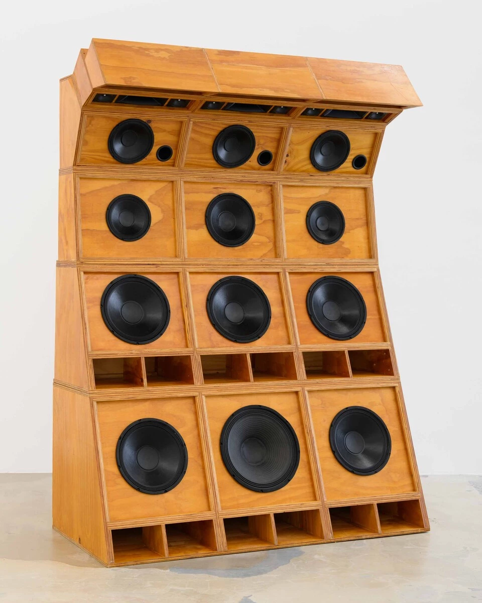 A wooden, 4-tiered speaker system that gets smaller in speaker size as it ascends and curves in like a wave